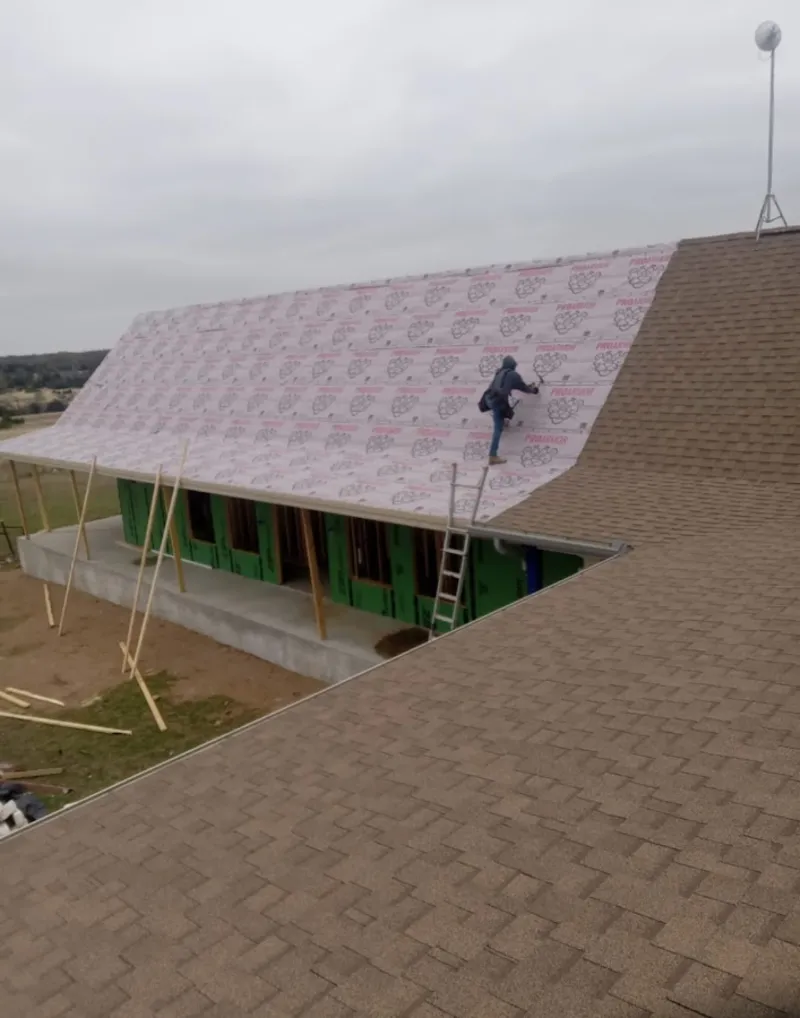 Worker preparing underlayment for a metal roof installation in St. Louis